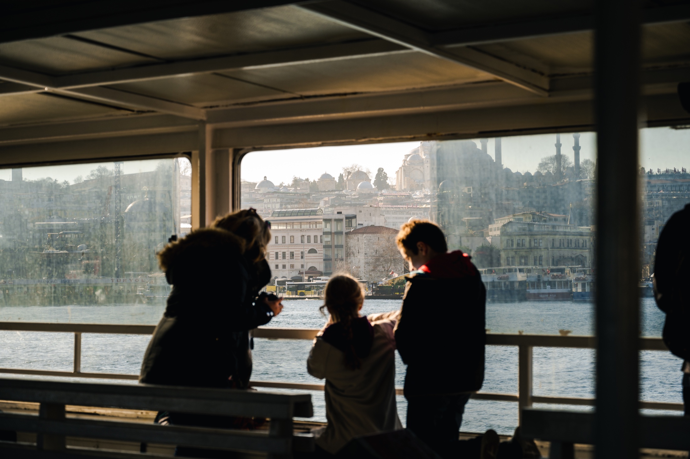Passengers looking across a city waterfront from a ferry
